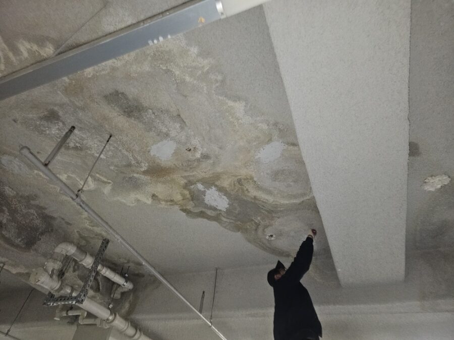 누수로 넓게 물자국이 번지고 마감이 벗겨진 천장과 노출된 배관